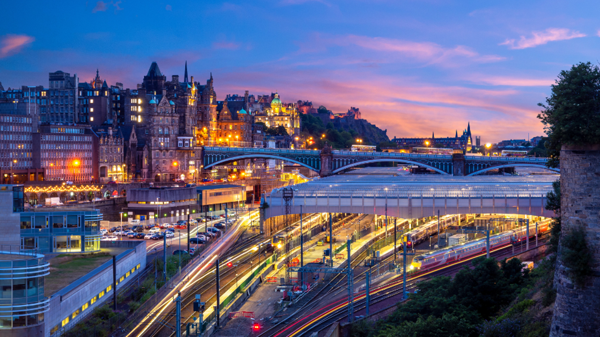 Trains leaving and arriving at a train station at dusk